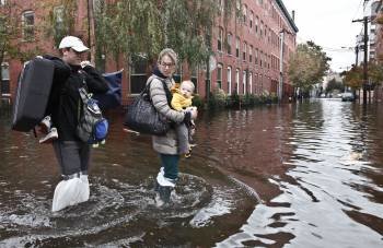 Una familia camina por una calle inundada de Hoboken, estado de Nueva Jersey. (Foto: KENA BETANCUR)