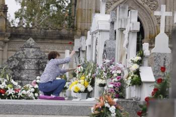 Una mujer cambia las flores de una sepultura en el cementerio de San Francisco el pasado jueves. (Foto: XESÚS FARIÑAS)