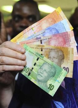 Un comerciante sostiene los nuevos billetes con la cara impresa del expresidente sudafricano Nelson Mandela