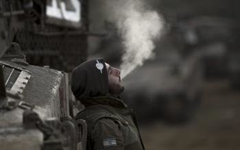 Un soldado israelí fuma un cigarro a primera hora de la mañana de hoy