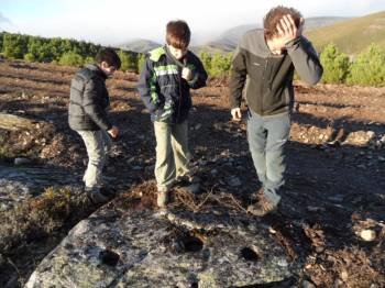 Jóvenes de Laza observan los daños ocasionados en la roca con la apertura de un cortafuegos.