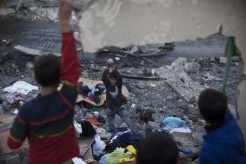 Niños recuperan ropa y juguetes de entre los escombros de una casa destrozada de la Ciudad de Gaza