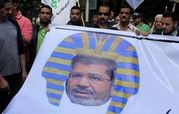 Mursi, caracterizado como un faraón en una pancarta portada por opositores a sus pretensiones. (Foto: ARCHIVO)