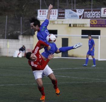 Luis González intenta despejar el balón ante un rival en el campo de Os Carrís. (Foto: XESÚS FARIÑAS)