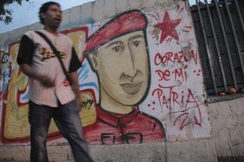 Un hombre camina frente a un muro en Caracas con la imagen del presidente de Venezuela, Hugo Chávez.