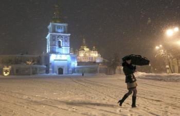 Una mujer camina junto a la catedral Mikhailovskiy durante una fuerte nevada caída en Kiev (Foto: EFE)