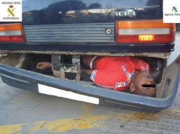 Un inmigrante escondido en los fondos de un vehículo.