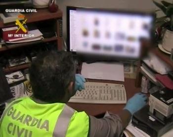 Imagen tomada del vídeo facilitado por la Guardia Civil que muestra a un agente con el material informático incautado en una de las dos operaciones contra la pornografía infantil en internet (Foto: EFE)