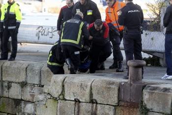 Varios bomberos izan el cuerpo sin vida aparecido frente al Náutico de Vigo. (Foto: SXENIC)