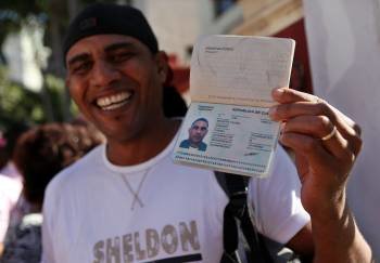 Un hombre muestra su pasaporte al salir ayer de la oficina de Inmigración y Extranjería en La Habana. (Foto: A. ERNESTO)