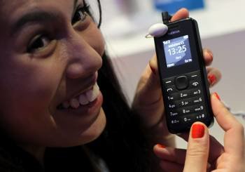Una azafata muestra el nuevo móvil que se presenta en Barcelona y que costará 15 euros. (Foto: TONI ALBIR)