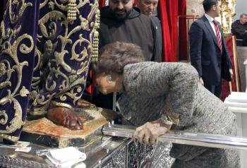 La Reina Doña Sofía se inclina para besar los pies del Cristo durante la visita que ha realizado hoy a la basílica de Jesús de Medinaceli.