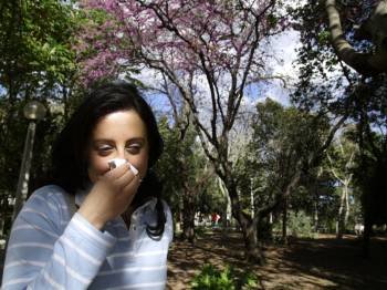 Una mujer sufre un episodio de alergia, que afecta ya a cuatro millones de españoles, mientras atraviesa un parque. 