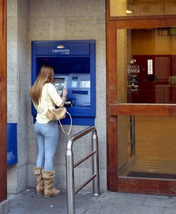 Una mujer retira dinero de un cajero de CajaCanarias.