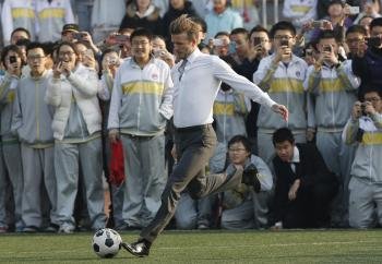 El futbolista británico David Beckham juega con estudiantes de un instituto en Pekín (China).