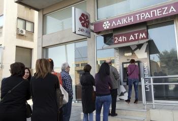 Varias personas hacen cola ante el cajero automático de una sucursal cerrada del Banco de Laiki en Nicosia (Chipre).