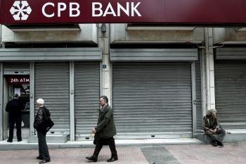 Un hombre saca dinero en efectivo en el cajero de una sucursal del Banco Popular de Chipre en Atenas.