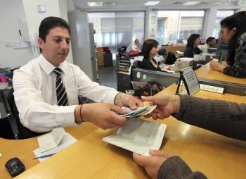 Un empleado del Banco Laiki entrega el dinero retirado por uno de sus clientes en Nicosia. (Foto: K. CHRISTODOULOU)