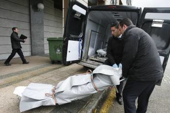 Agentes de los servicios funerarios proceden al traslado de uno de los cadáveres. (Foto: EL CORREO GALLEGO)