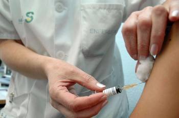 Una enfermera pone una vacuna en el brazo de un joven durante un control médico. 