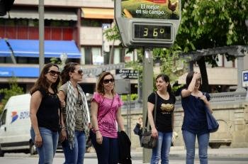 Varias personas pasan ante un termómetro del centro de la ciudad, que marca 36º al sol  (Foto: EFE)