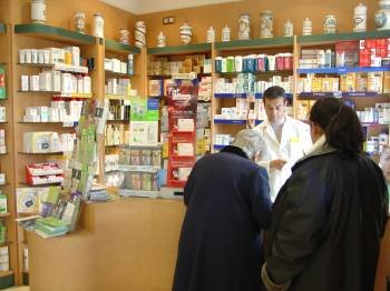 Un empleado de una farmacia dispensa medicamentos a una mujer en el establecimiento