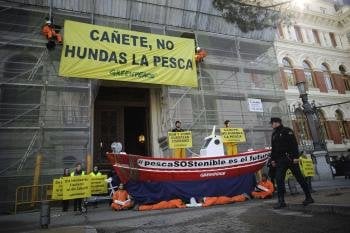 Activistas de Greenpeace durante la protesta que han protagonizado hoy en Madrid en la que han mostrado una gran pancarta con la inscripción 'Cañete, no hundas la pesca'