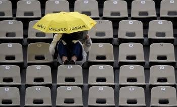 Un espectador se protege de la lluvia bajo un paraguas después de que los partidos del torneo de Roland Garros hayan sido aplazados por la lluvia.