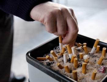Un ciudadano apaga un cigarrillo en un cenicero público. (Foto: ARCHIVO)