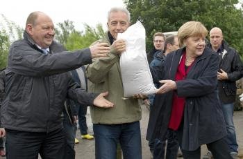 Merkel carga sacos de arena tras las inundaciones en Alemania. (Foto: arno burgi)