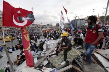 Varios activistas turcos ondean bandera nacionales en el parque Gezi, situado en la plaza Taksim. (Foto: SEDAT SUNA)