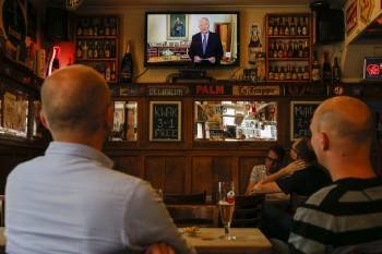 Varias personas observan el discurso televisado de Alberto II en un bar de Bruselas. (Foto: THIERRY ROGE)