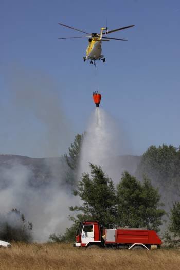 Un helicóptero arroja agua sobre las llamas. (Foto: XESÚS FARIÑAS)