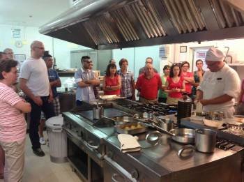 Los participantes observan la preparación de uno de los platos en las instalaciones Parador.