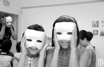 Dos niños que participan en el taller, hacen una prueba con las máscaras que elaboran en el taller.