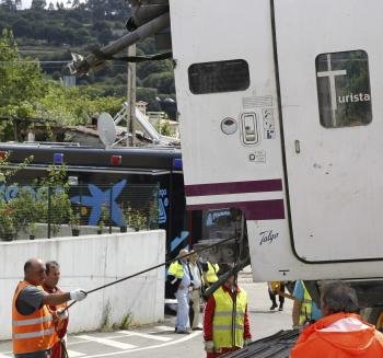 Operarios trabajan en el desmontaje y traslado de uno de los vagones del convoy siniestrado en el descarrilamiento de un tren ocurrido anoche en Santiago de Compostela (Foto: efe)