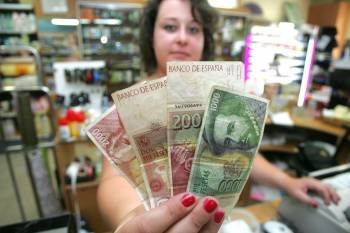 Una comerciante muestra billetes que ha reunido en la campaña 'Benditas pesetas'. (Foto: FOTOS: MARCO ATRIO)