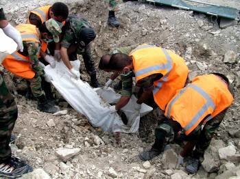 Miembros de la defensa civil de Siria trasladan un cuerpo de una tumba común en la provincia de Lattakia.  (Foto: SANA)