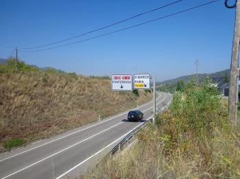 Un vehículo circula por la carretera N-120, a su paso por O Barco, con carteles indicando Rubiá y Ponferrada. (Foto: J.C.)