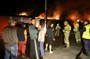Vecinos de la parroquia de Asados osbservan las llamas junto a un grupo de brigadistas. (Foto: SXENICK)