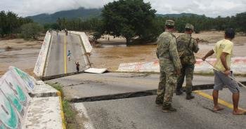 Habitantes cruzan ayudados por miembros del Ejército un puente colapsado (Foto: efe)