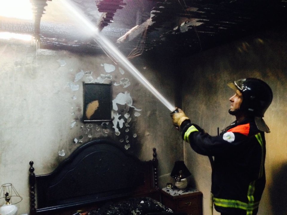 Un bombero sofoca los restos del fuego que afectó a una vivienda en Proente (A Merca) (Foto: José Paz)