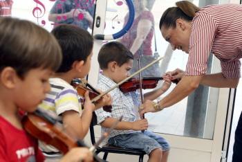 Un grupo de niños, durante una de sus primeras clases de violín al lado de Helena Colina. (Foto: MORELL)