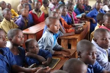 Un grupo de niños africanos asiste a clase en una escuela rural.
