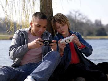 Dos jóvenes juegan conectados con sus videoconsolas. 