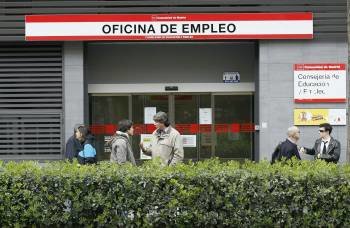 Un grupo de personas espera en las puertas de una oficina de empleo.
