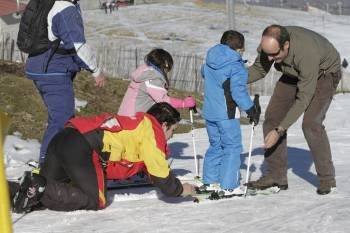 Dos personas ayudan a un pequeño a colocarse bien su equipo de esquí. (Foto: MIGUEL ÁNGEL)