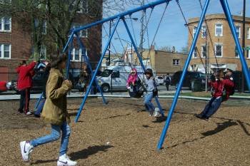 Un grupo de niños juega en los columpios de un parque.