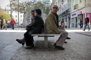 Un grupo de personas mayores sentado en un banco de la calle.