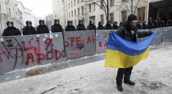 Un manifestante posa con una bandera ante una fila de policías antidisturbios, en Kiev. (Foto: ZURAB KURTSIKIDZE)